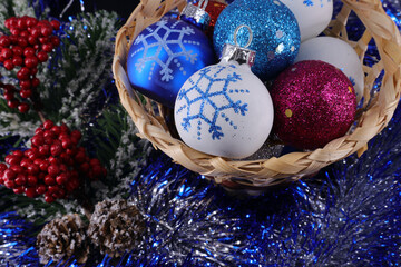 decorations for the celebration of the new year - Christmas balls in a wicker basket, tinsel, red berries, fir branch