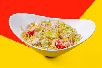 Caesar salad with chicken breast on yellow and red background