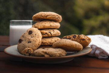 Cookies pile on a plate with a glass of milk