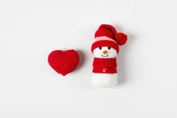 A knitted snowman and a red heart on a gray background. Winter Christmas holiday concept