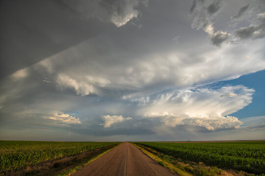 Storm clouds gather over a road that leads into the distance, creating a very dramatic landscape; North Dakota, United States of America