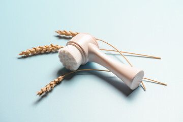 Facial brush with wheat spike on blue background.