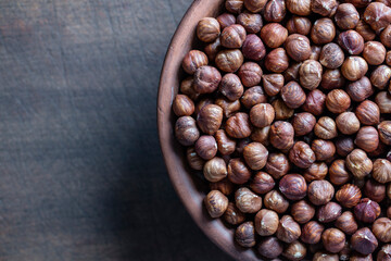 Dry hazelnuts in a ceramic plate on a wooden background. Heap of peeled hazelnuts kernels, top view, copy space for text