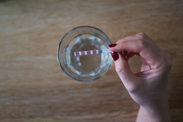 Woman's hand holding  analysis strip test, checking water hardness at home. Indicator shows very hard water.  Table top view, selective focus. - obrazy, fototapety, plakaty