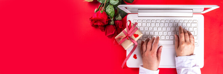  Valentine day simple background, Woman using laptop, with gift bow with festive tied ribbon, heart decor, on bright red background. Online Valentine`s shopping, preparation for February 14 holiday.  - Powered by Adobe