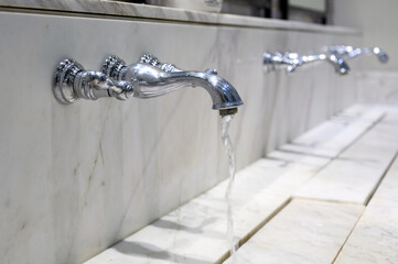 Water tap, Water drop from chrome faucet to washbasin. Hygiene concept.