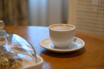 Hot Coffee in white cup on wooden table in kitchen room at comfort home.