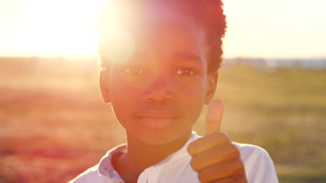 Black child, face or thumbs up in sunset nature park for adoption success, relief aid or charity donation for Congo poverty. Portrait, boy or kid with yes hand gesture in community volunteer support