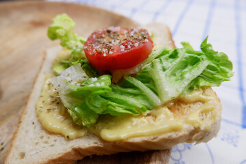 Sandwich mit Creme, Tomaten, Salat und Gewürzen