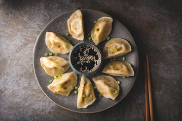 Chinese dumplings on a plate, soy sauce and chopsticks. Traditional Chinese/Asian dish. Dim sum dumplings steamed in a steamer