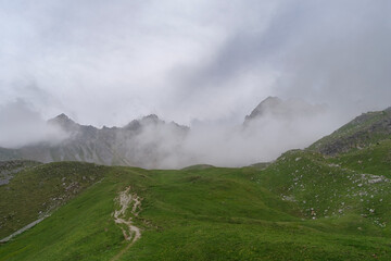 Hiking in Maira Valley, Italy. Mountain peaks emerging from the clouds