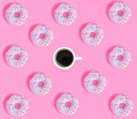 Donut with pink glaze and coffee cup on the pink background. Flat lay. Pattern. Top view.