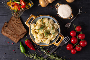 boiled dumplings with sour cream and gray bread, on a black background