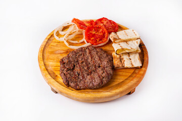 steak with fried tomatoes and onions on a round wooden board.  white background