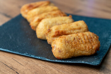 Ración de croquetas servidas en plato negro pizarra