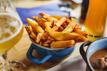 Portion of crispy golden spiced potato wedges in a blue bowl restaurant serving french fries....