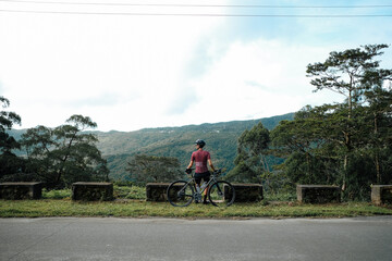 A young female cyclist looking at a view in the mountains during her bike ride.