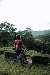 Obraz premium A young female cyclist looking at a view in the mountains during her bike ride.