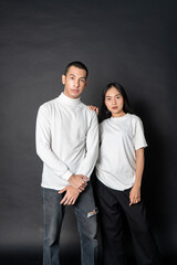 Young couple wearing white blank shirt doing a pose with a black background