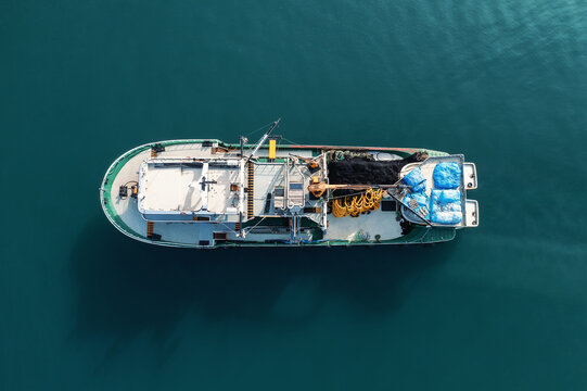 Fishing boat aerial top view from drone on sea surface. Fishing and seafood industry.