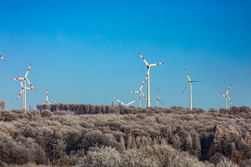 Wind turbines on the winter hill.  Wind farm against blue sky. Producing electric energy. Renewable energy. Wind park.