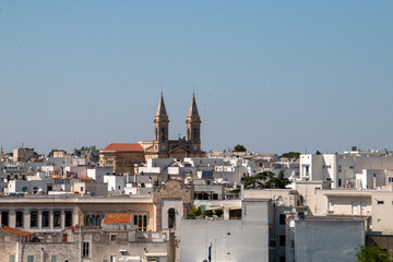 Campanarios de la Basílica santuario de San Cosme y Damián en Alberobello, Italia. Tejados y azoteas de los edificios que rodean el templo cristiano.