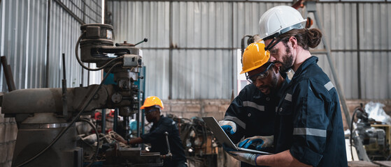 Industrial engineers inspect and perform maintenance on the machines at factory machines.