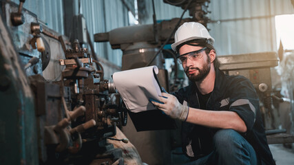 Industrial engineers inspect and perform maintenance on the machines at factory machines.