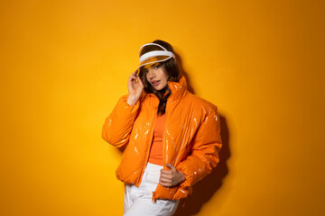 Beauty latino female with hood and jacket on orange background with shadow.