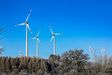 Wind turbines on the winter hill.  Wind farm against blue sky. Producing electric energy. Renewable energy. Wind park.