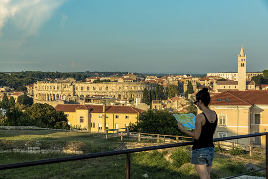 Female tourist with map at ancient Roman Amphitheatre known as Pula Arena; Pula, Istria, Croatia