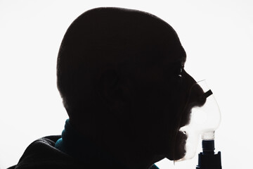 Front view silhoutte of an old bald man with asthma using a nebulizer - obrazy, fototapety, plakaty
