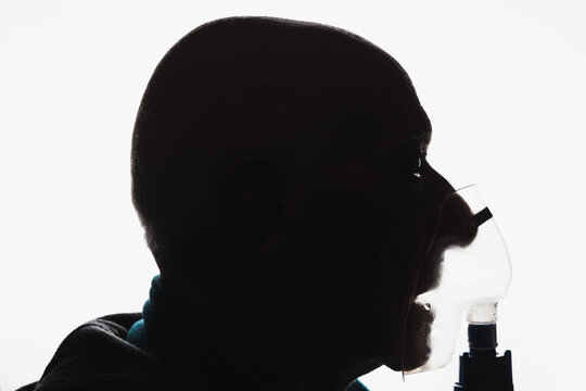 Front View Silhoutte Of An Old Bald Man With Asthma Using A Nebulizer