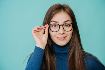 close-up portrait of a pretty Swedish girl, amazed woman with perfect skin, she touches glasses in surprise expression over turquoise backdrop. People emotions. Mockup, model at studio.