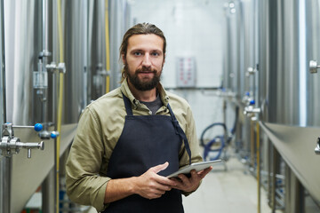 Beer brewery worker with tablet computer checking every production process