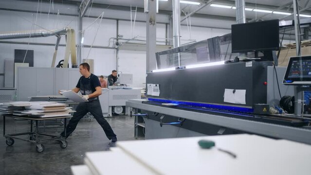 edge banding process in furniture factory, man using modern CNC machine for making chipboard details