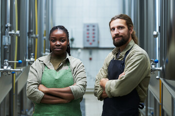 Smiling team of microbrewery workers standing with arms crossed