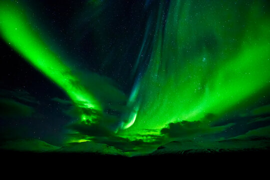 Bright green aurora borealis swoops across the night sky; Iceland