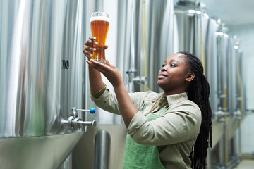 Proud brewery owner looking at glass of fresh beer