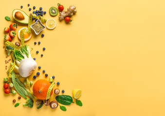 Set of fresh vegetables, fruits and berries for healthy diet food on yellow background with measuring tape, copy space top view. Dietary