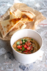Pita with assorted traditional greek dips vegetable caviar specialty baba ganoush with fresh tomatoes and parsley over light background.