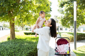 Naklejka premium Beautiful mom holding a baby girl in her arms outdoor in sunshine day.