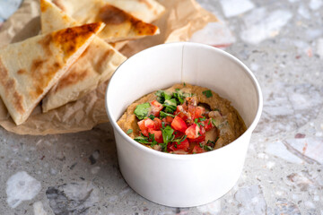 Pita with assorted traditional greek dips vegetable caviar specialty baba ganoush with fresh tomatoes and parsley over light background.