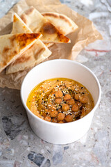 Pita with hummus over light background. Food for delivery.