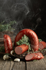 Smoked sausage with thyme and garlic on a wooden table.