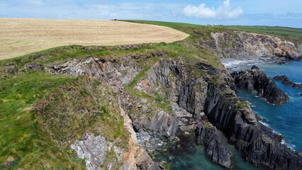Fototapeta na wymiar Farm fields on the shore of the Celtic Sea, south of Ireland, County Cork. Beautiful coastal area. Turquoise waters of the Atlantic. Picturesque stone hills. View from above.