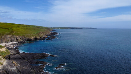 Fototapeta na wymiar Green hills on the Atlantic Ocean on a sunny spring day. Blue sky over the sea coast. The coastline of Ireland, West Cork. Aerial photo. Drone point of view.