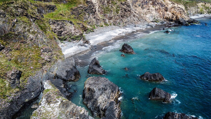 Steep cliffs on the coast. Turquoise waters of the Atlantic Ocean. Natural beauties of Ireland, West Cork. The rocky coast of the Celtic Sea. Drone point of view.