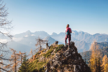 One lonely woman hiker standing in top of the rock looking at the breathtaking view of the mountains