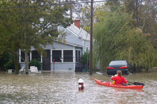 A Woman With Her Two Year Old Boy, Paddles A Sea Kayak Down A Street.Flooding From A Strong Norï¿½easter On The Lower Chesapeake Bay. This Beach Neighborhood In Hampton, VA Has More Frequent Flooding 